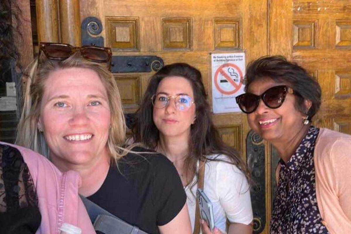 three women posing for a picture in front of a door