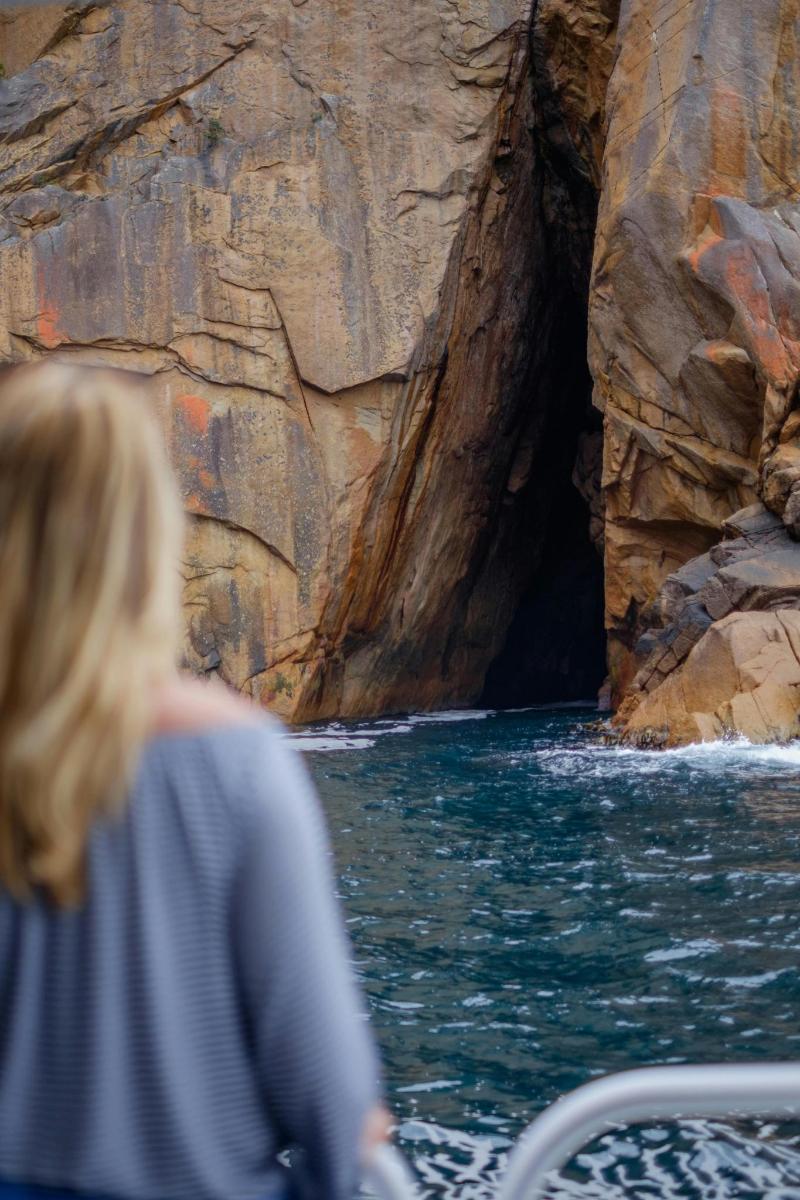 a woman on a boat in the water near a cave