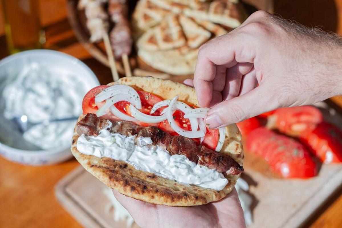 una persona sosteniendo un sándwich de salchicha con cebollas y tomates