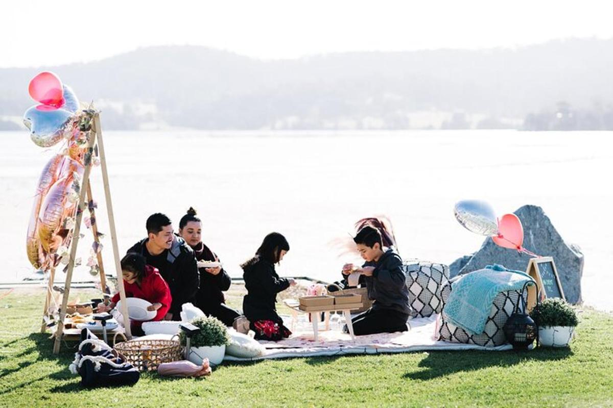 a group of people sitting on the grass near the water