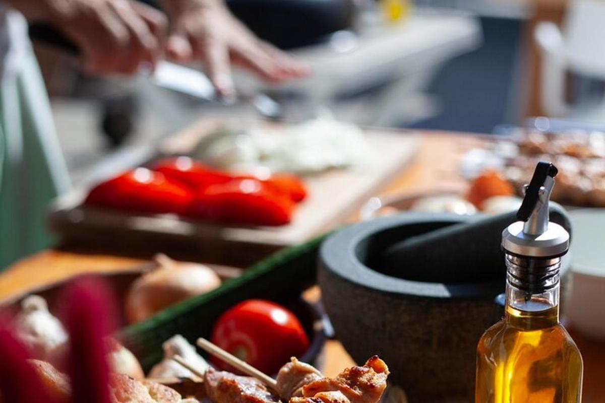 Una mesa con una botella de aceite y verduras encima.