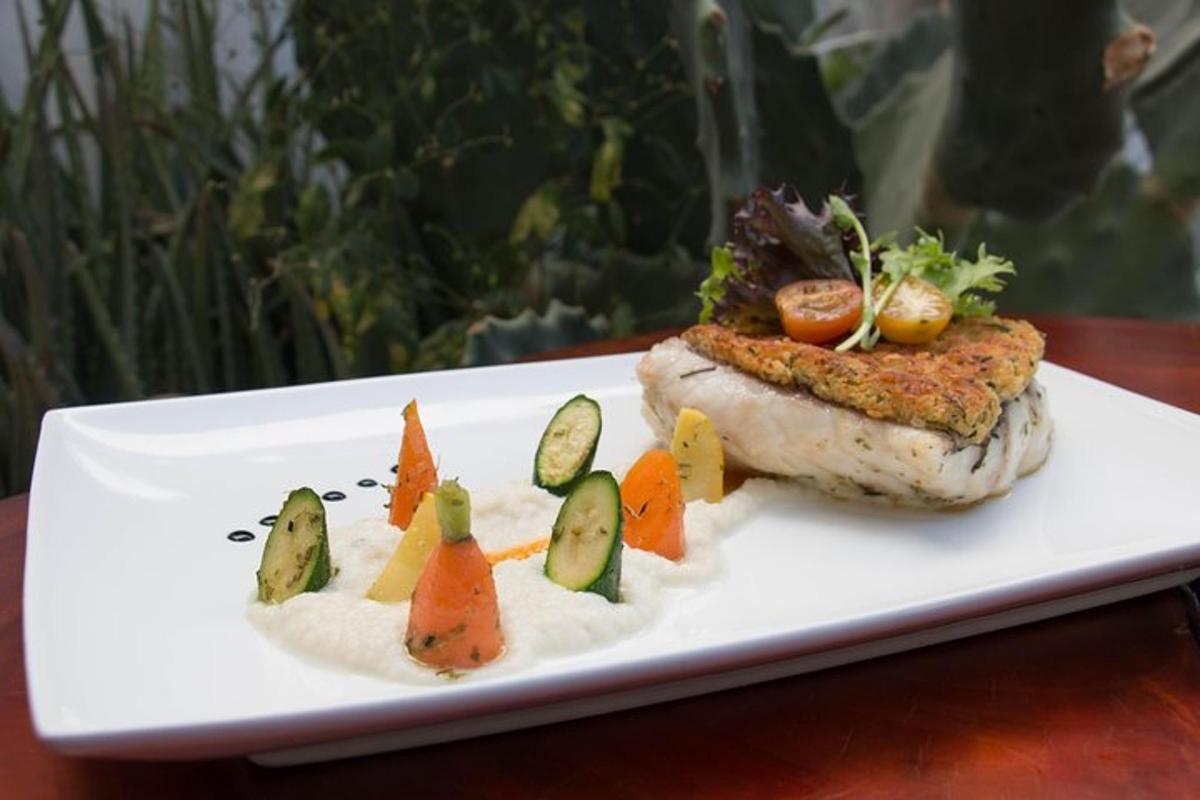 Un plato blanco con un trozo de pescado con verduras encima.