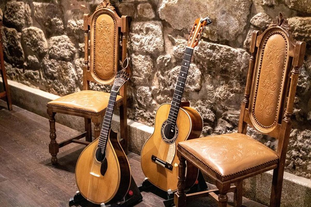 dvi akustinės gitaros, sėdinčios ant kėdžių priešais akmeninę sieną