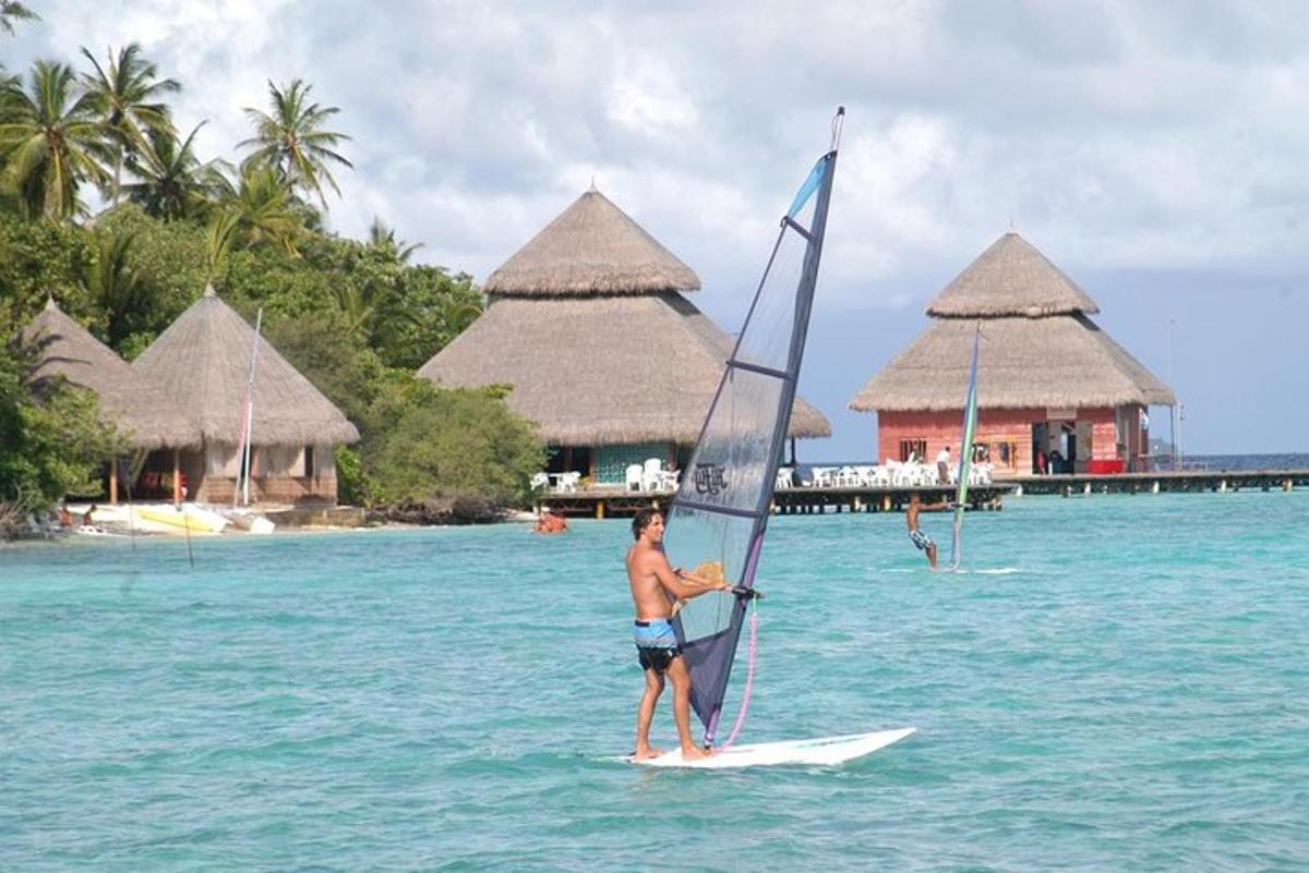 a man on a surfboard with a sail on the water