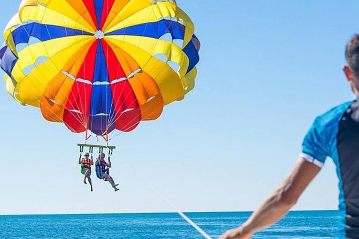 un bărbat care zboară cu o parașută colorată deasupra oceanului