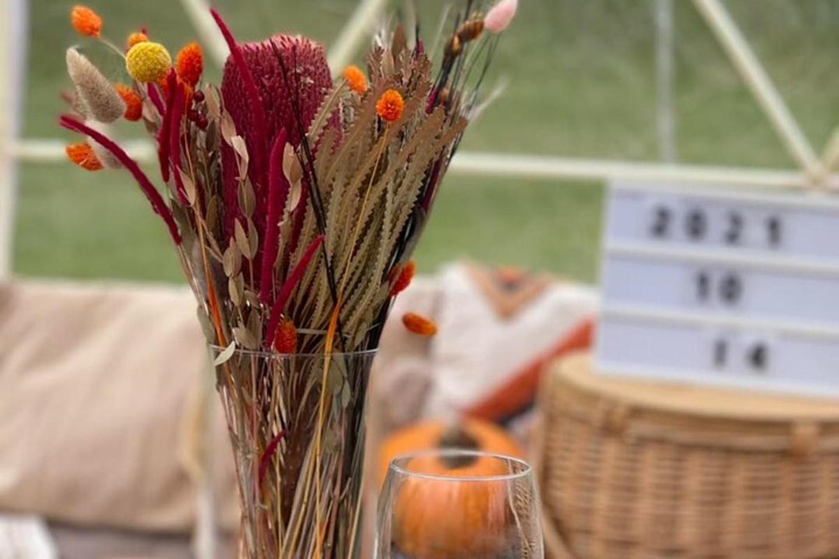 váza s květinami stojící na stole se sklenicí