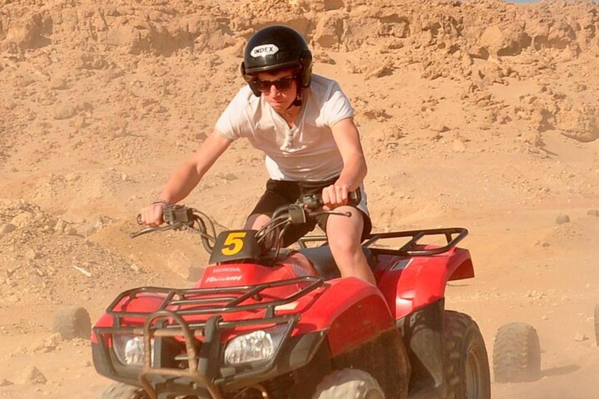 un home que condueix un quad a la sorra