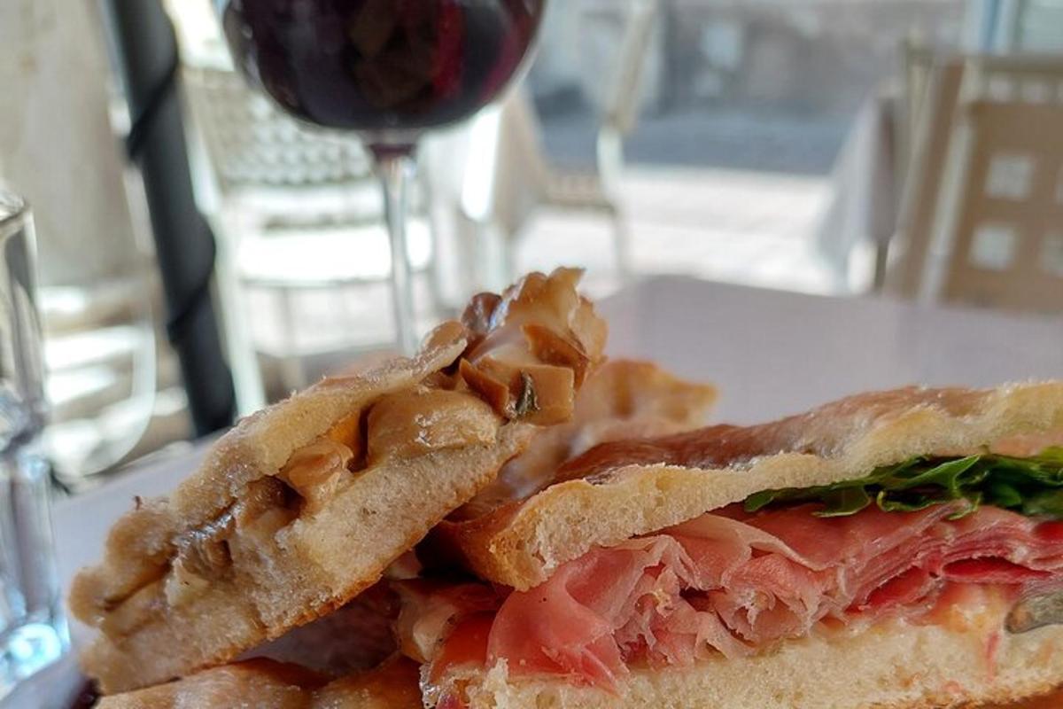 un panino tagliato a metà su un piatto con un bicchiere di vino