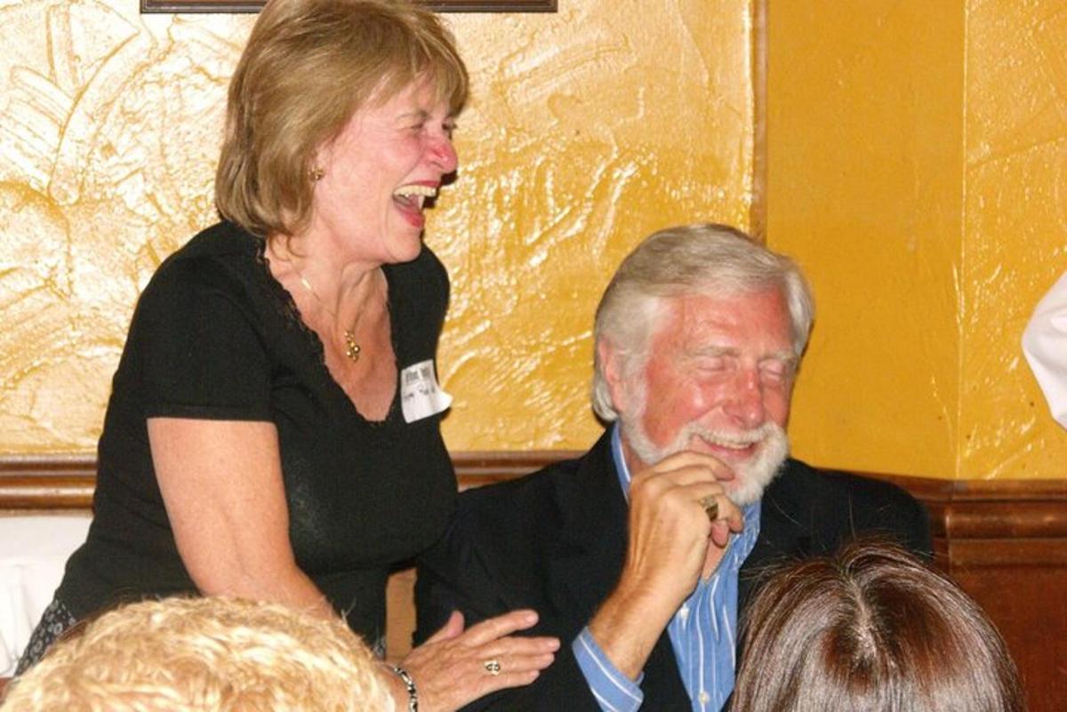 a woman standing next to a man sitting down