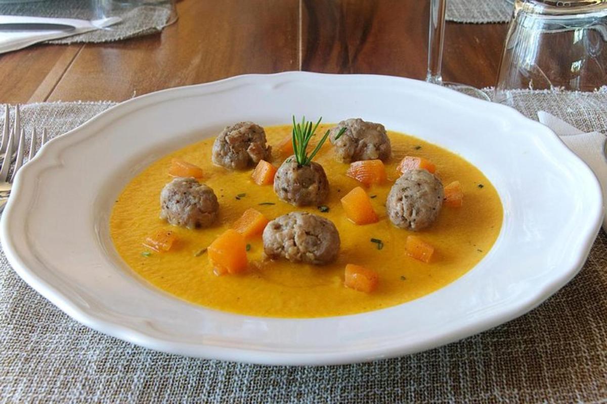 Un plato blanco de sopa con albóndigas y zanahorias