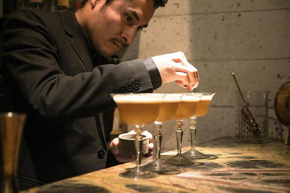 um homem de terno está preparando duas taças de martini