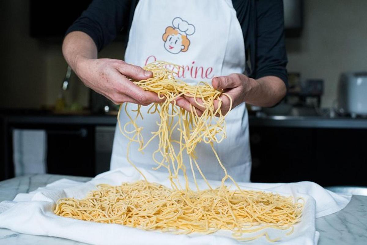 en person på kjøkkenet som holder en haug med spaghetti