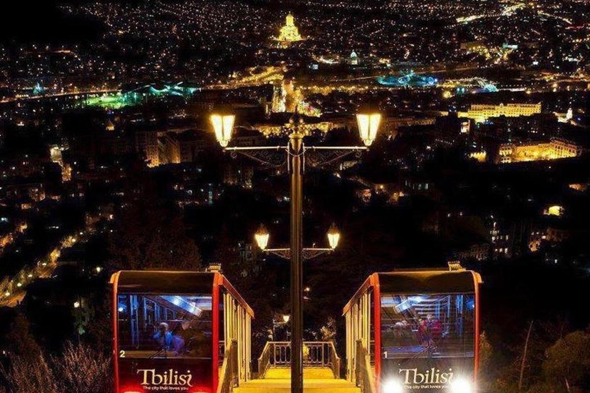 Dos tranvías rojos estacionados al lado de una ciudad por la noche