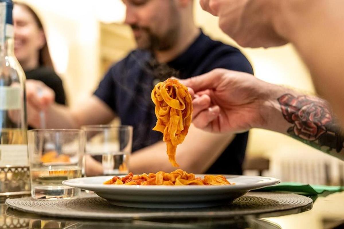 una persona che tiene un piatto di pasta su un tavolo
