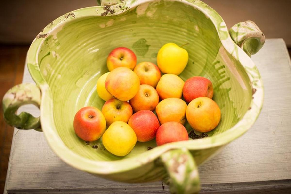 een groene mand gevuld met appels en citroenen op een tafel