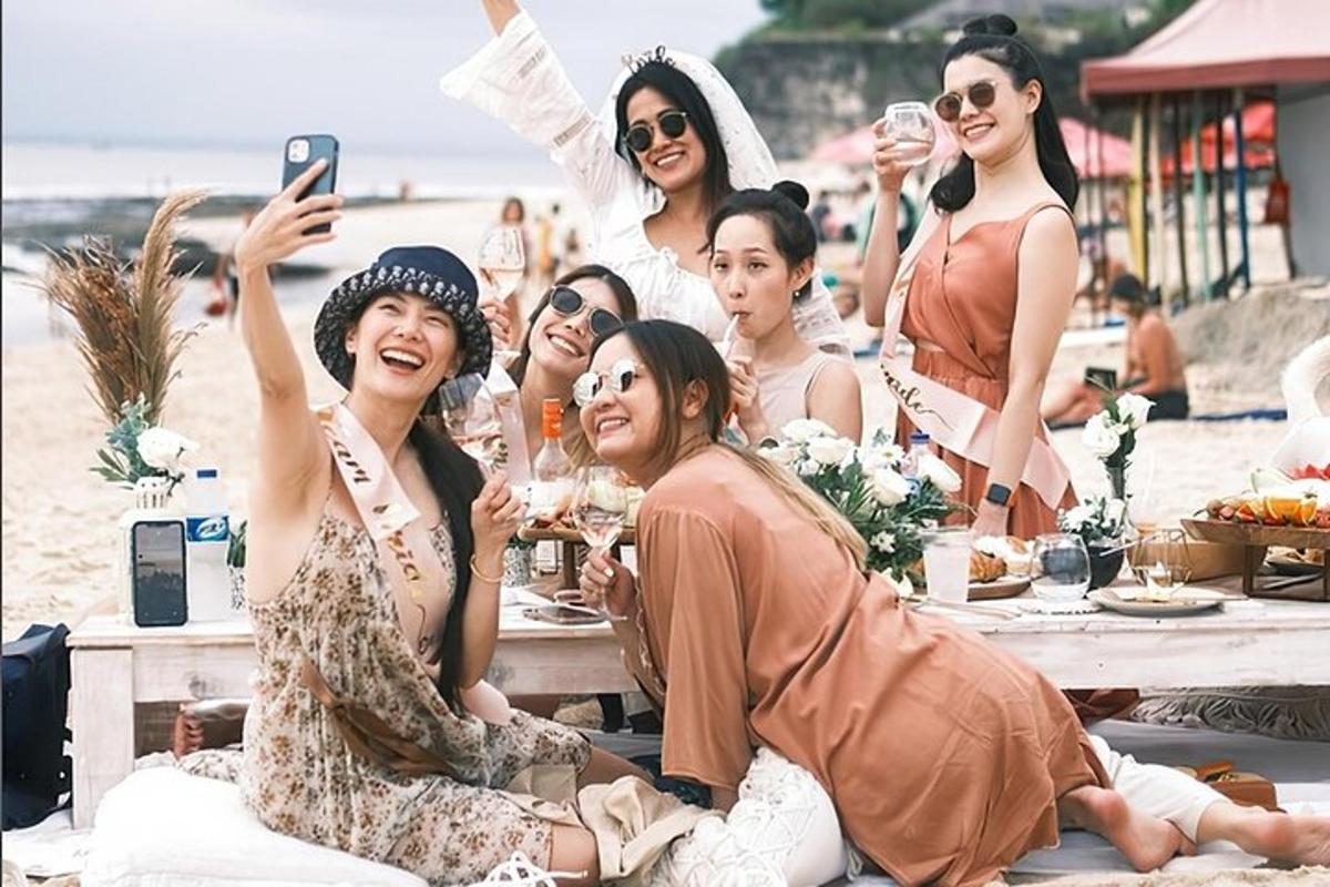 a group of women sitting around a table on the beach