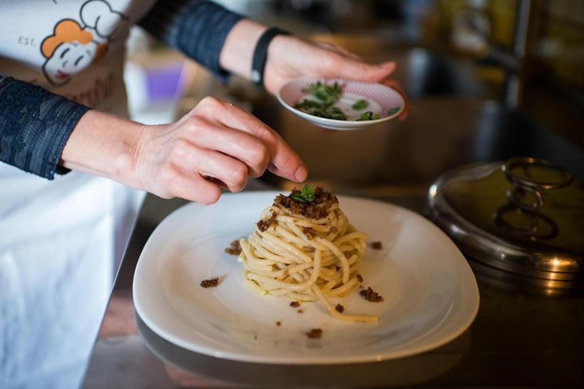a person holding a bowl of pasta on a plate
