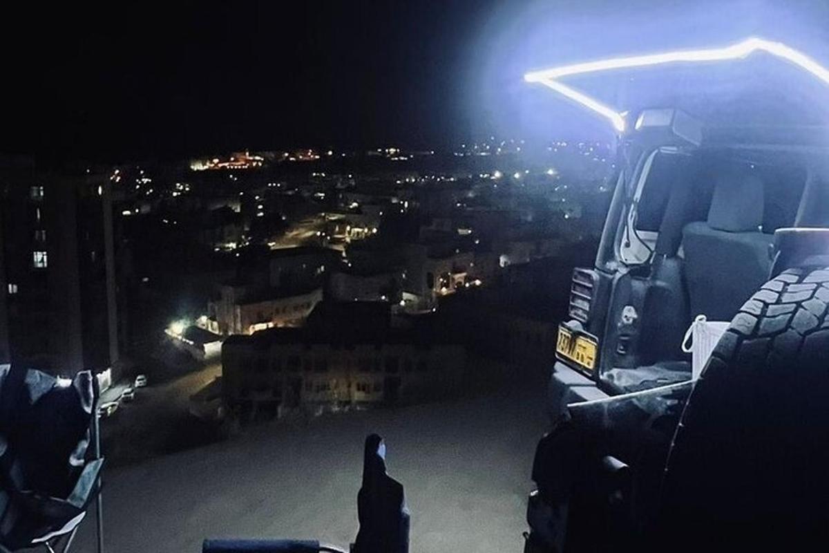 uma pessoa sentada na frente de um caminhão semirreboque à noite