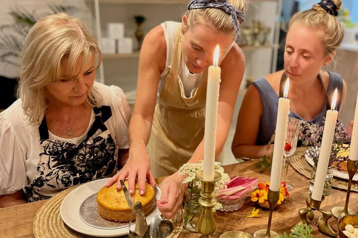 three women standing around a table cutting a cake