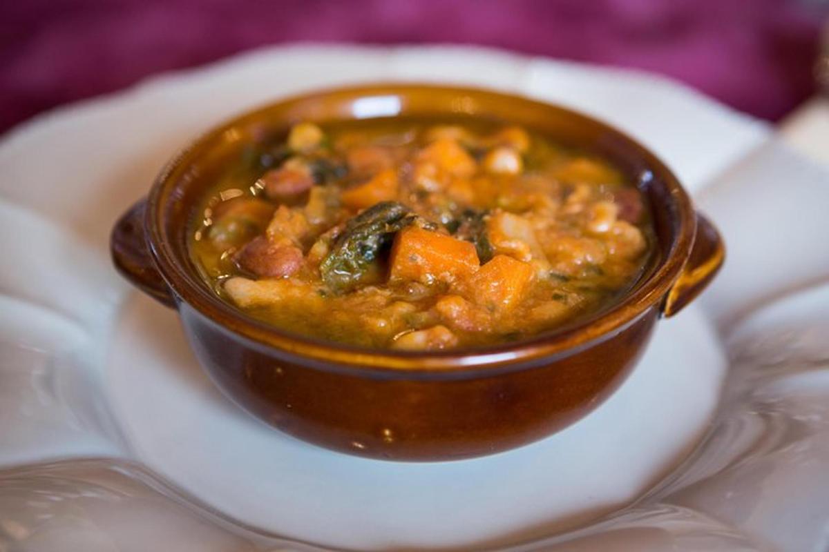 una ciotola marrone di zuppa su un piatto bianco