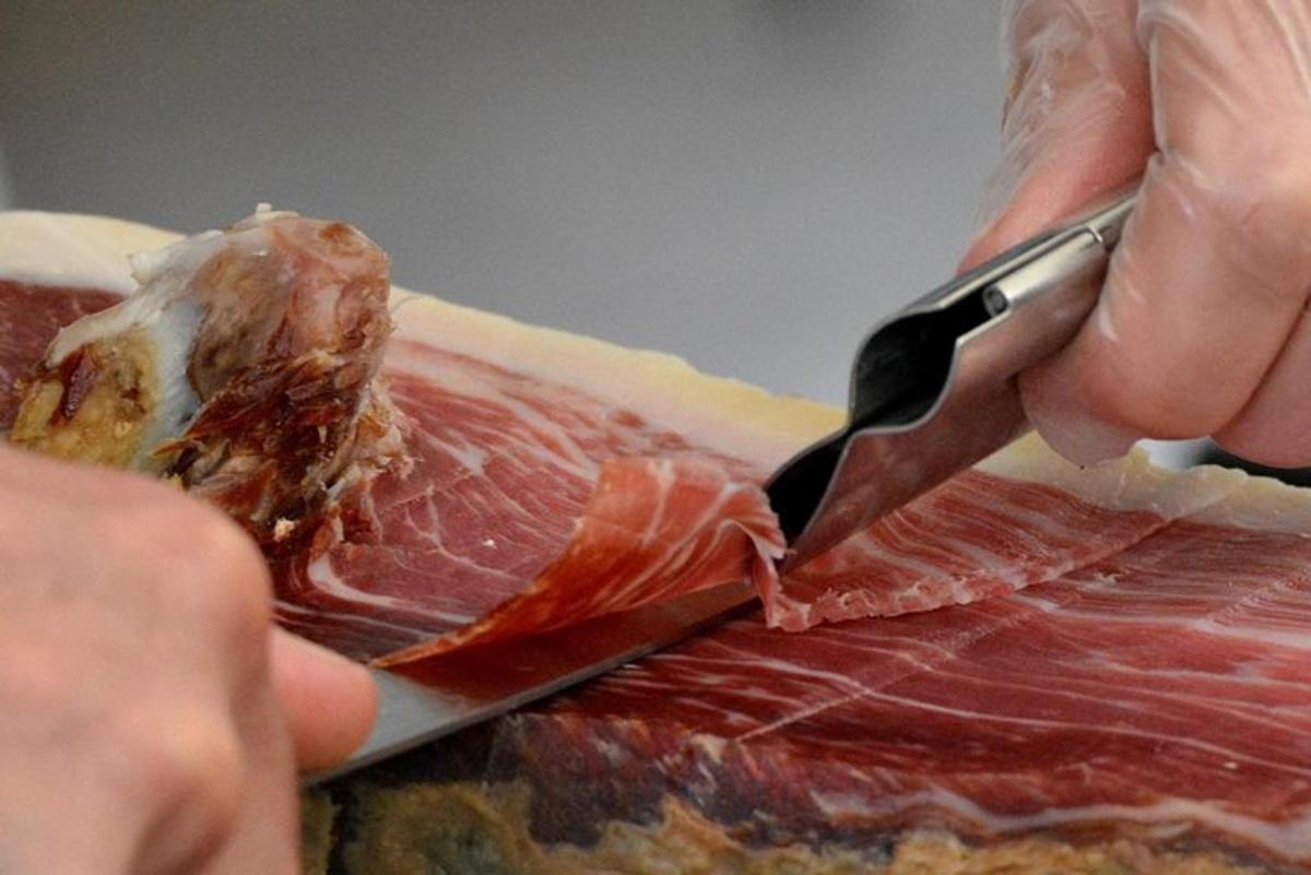 una persona che taglia un pezzo di carne con un coltello