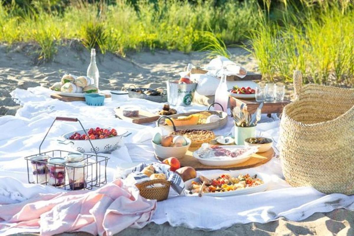 berkelah di pantai dengan makanan di atas selimut