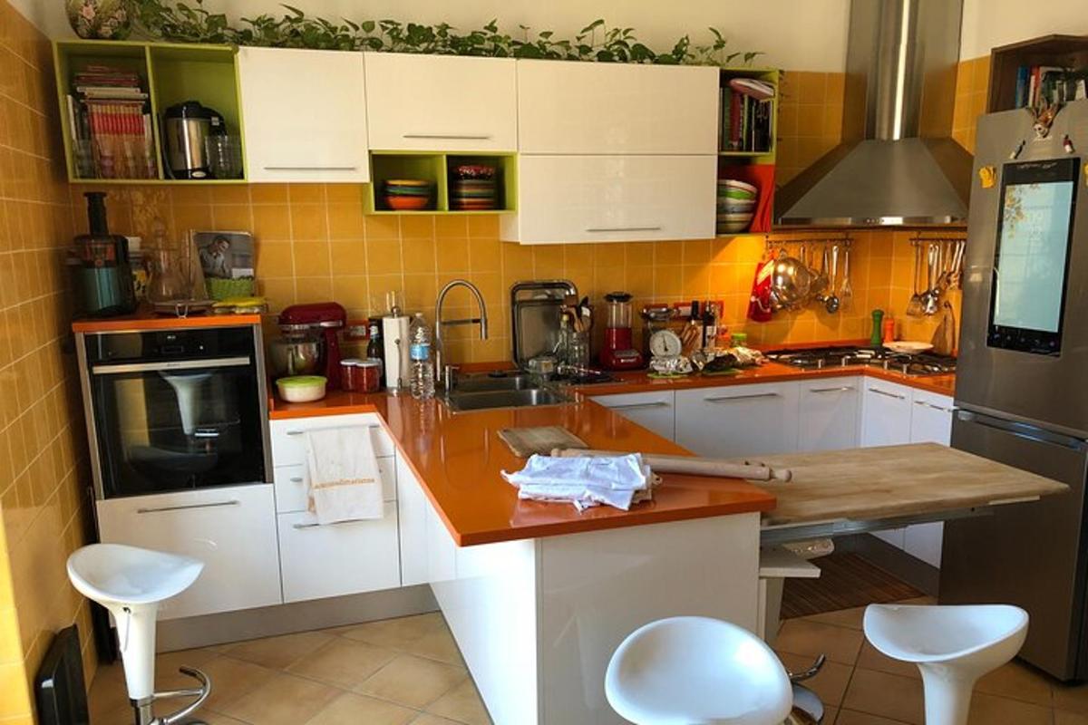 Una cocina con gabinetes blancos y una encimera con taburetes.