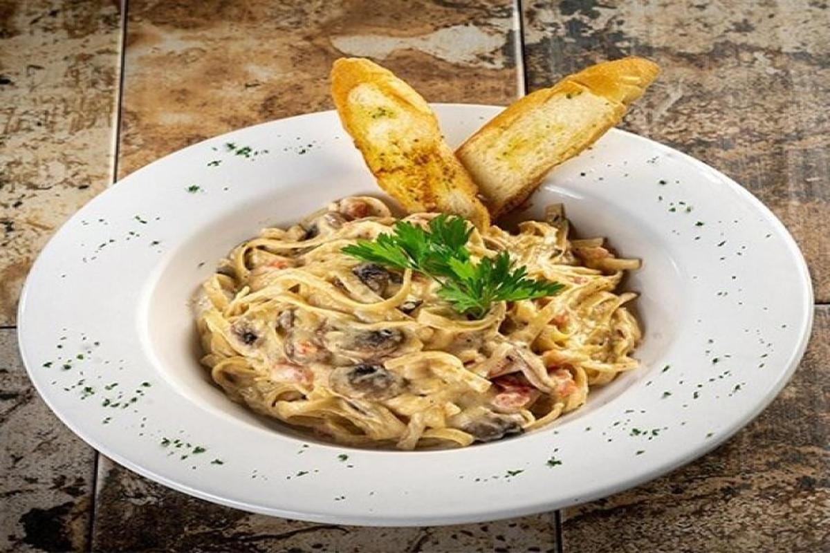 una ciotola di pasta con funghi e un paio di utensili