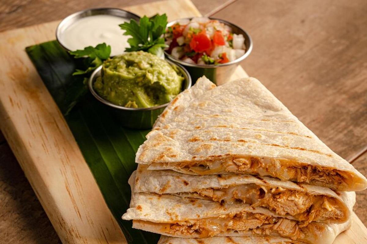 un panino su un tagliere con due ciotole di guacamole