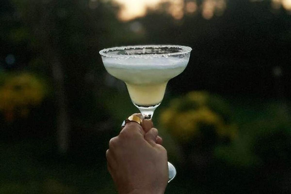 una persona che tiene in mano un drink in un bicchiere da martini