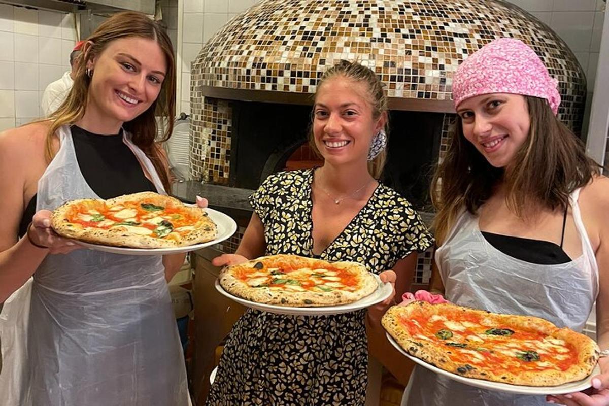 tri ženy držiace pizze v kuchyni