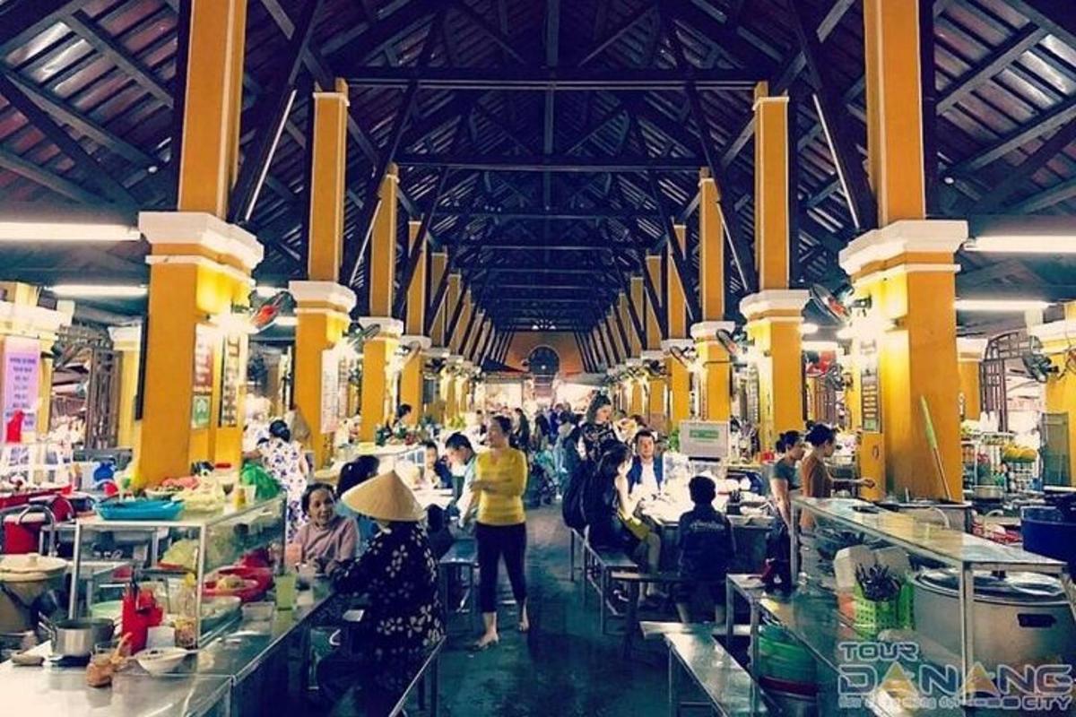Un grupo de personas sentadas en mesas en un mercado.