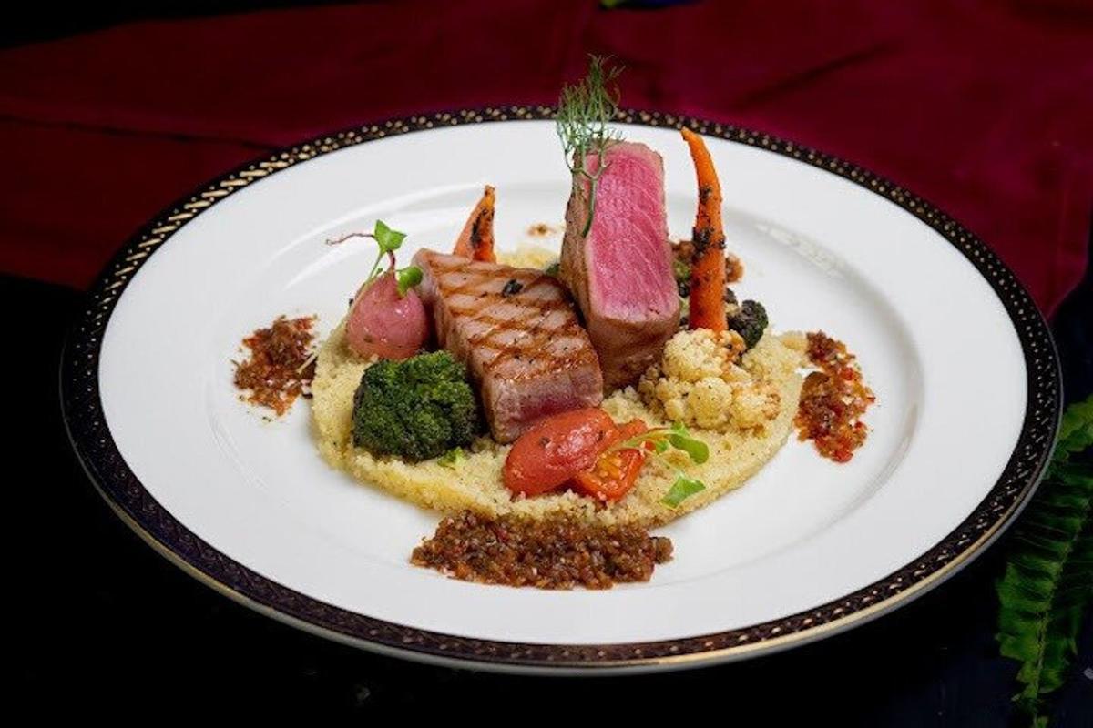 Un plato de comida con carne y verduras encima.