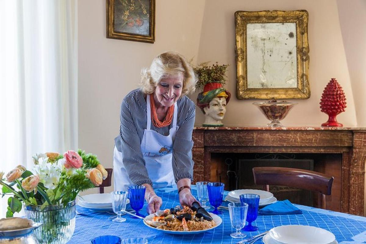 una donna anziana in piedi a un tavolo con un piatto di cibo