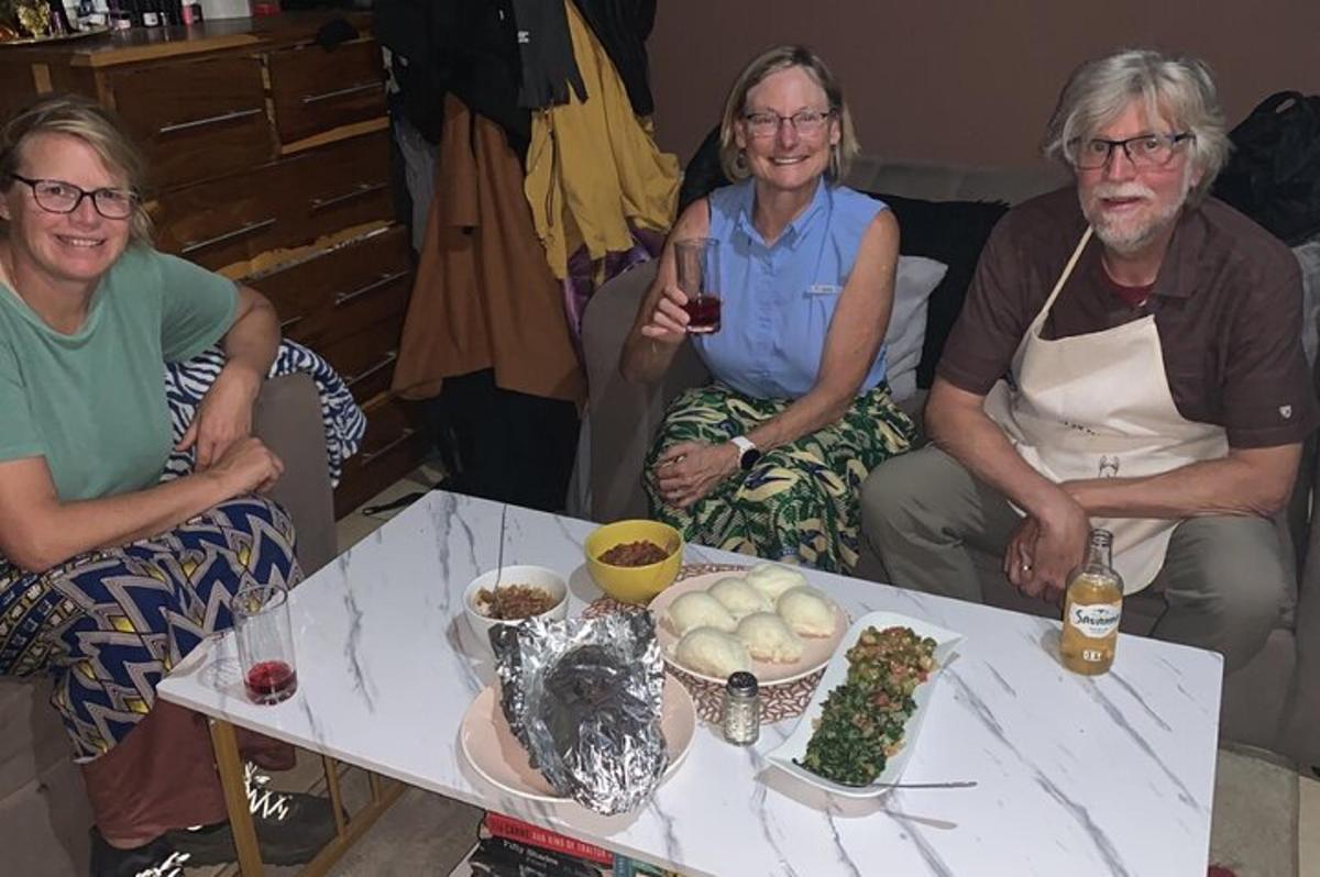 a group of three people sitting around a table with food