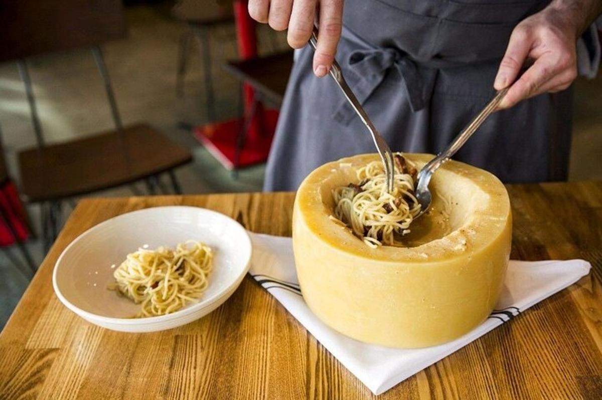 en person, der spiser en skål spaghetti med en gaffel