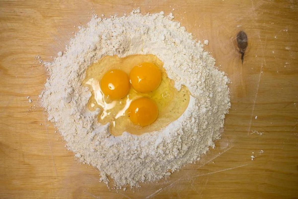 zwei Eier in einer Schüssel mit Mehl auf einem Schneidebrett