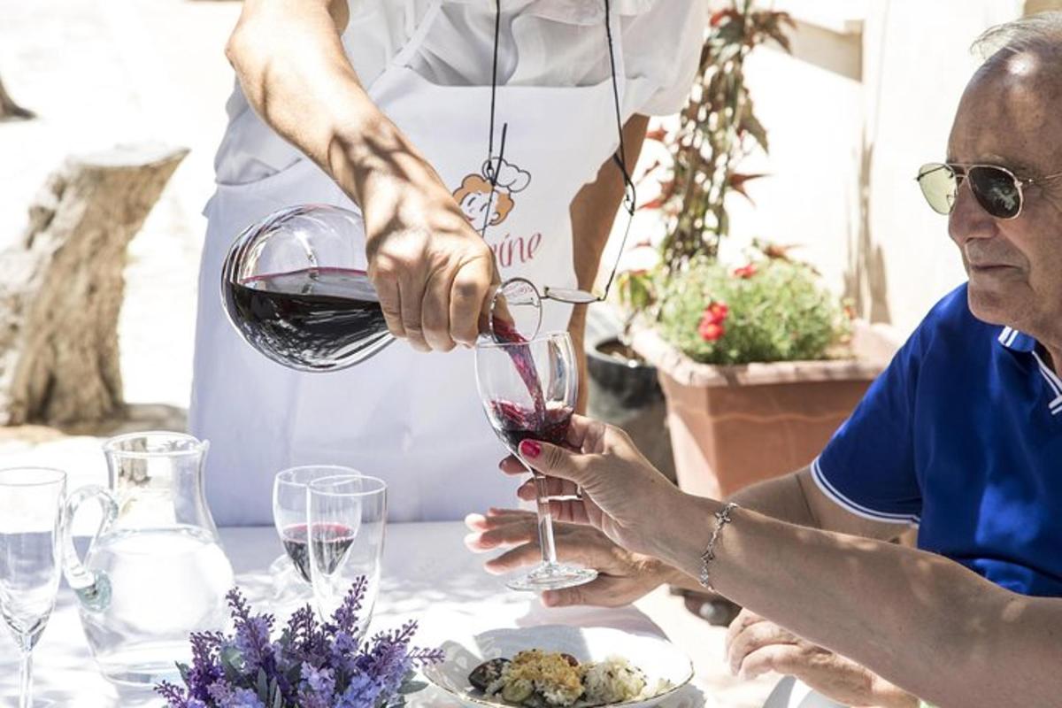 o femeie mai în vârstă care își toarnă un pahar de vin roșu