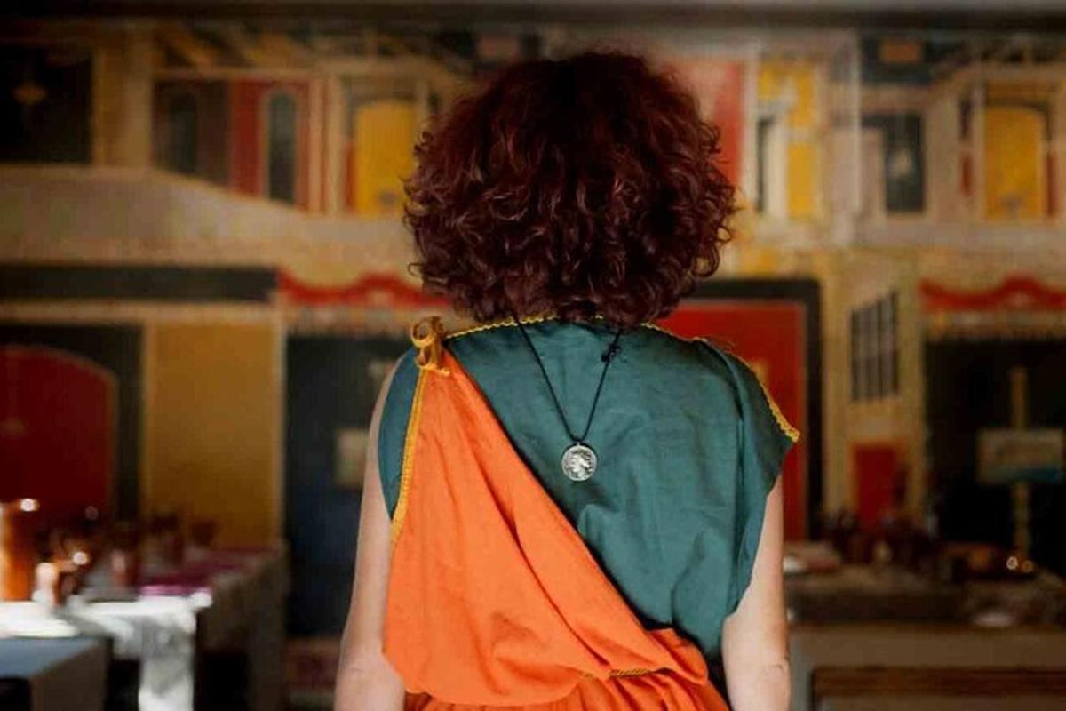seorang wanita memakai gaun berwarna oren dan hijau