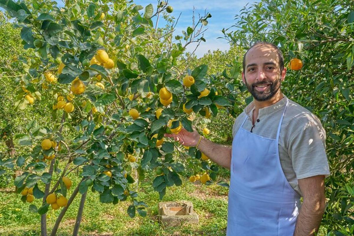 un home amb un davantal blau dret al costat d'un llimoner
