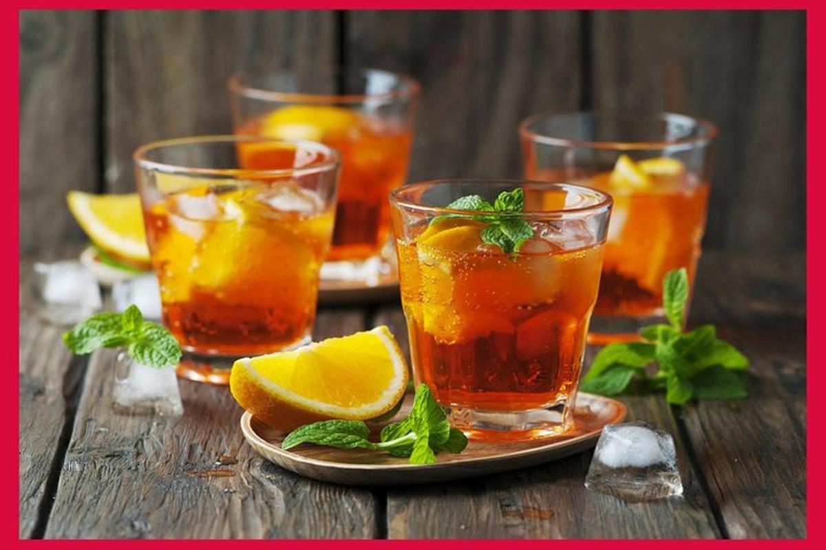 four glasses of tea with orange slices on a wooden table
