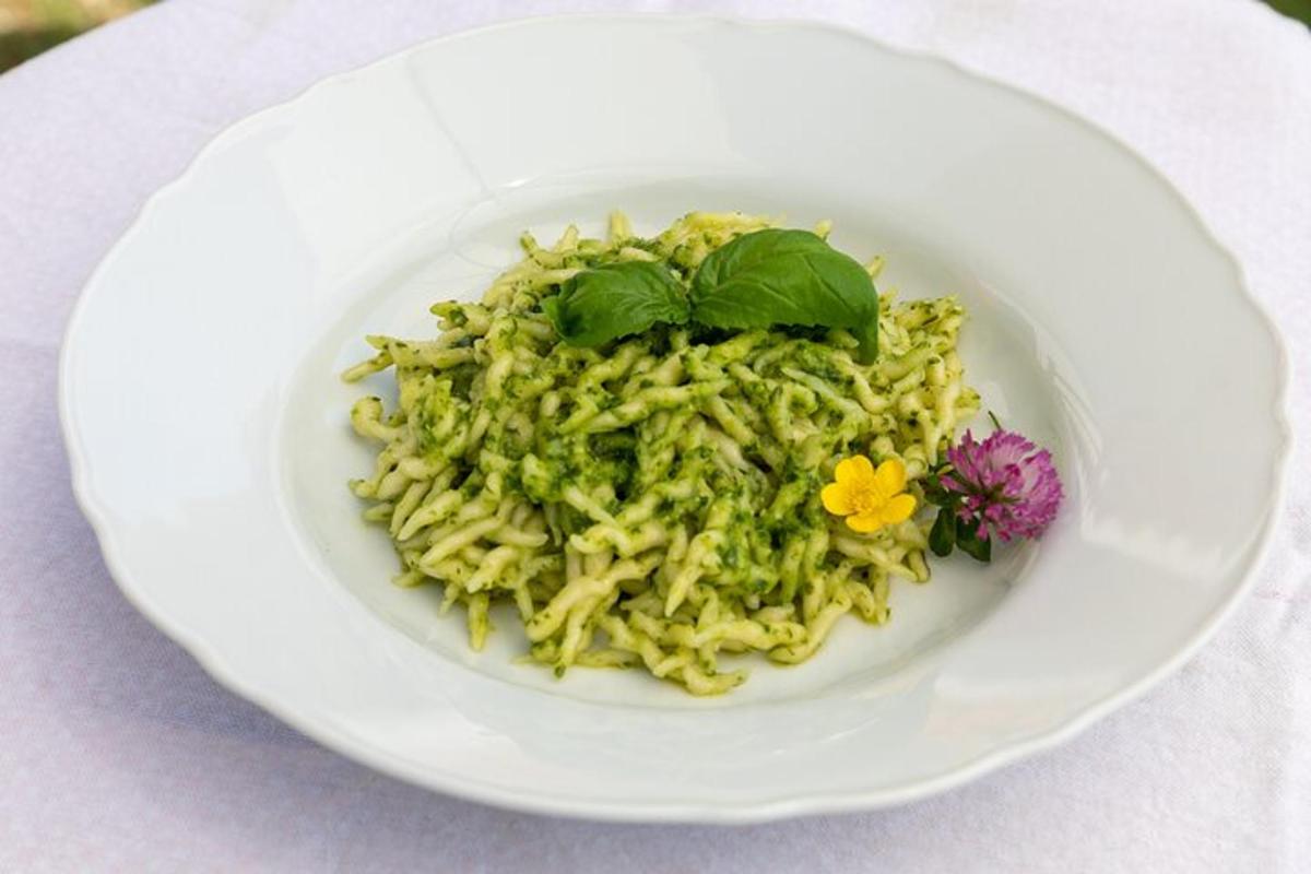 a white bowl of pasta with flowers on a table