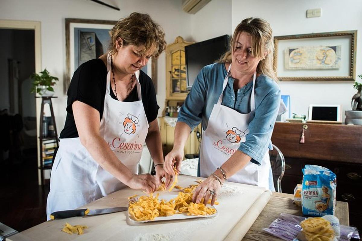 Dos mujeres en una cocina preparando comida en una mesa.