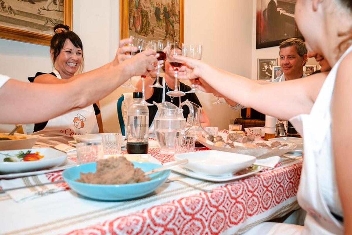een groep mensen die rond een tafel zitten en wijn drinken