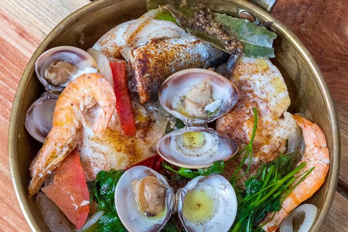 a bowl of food with shrimp and oysters on a table