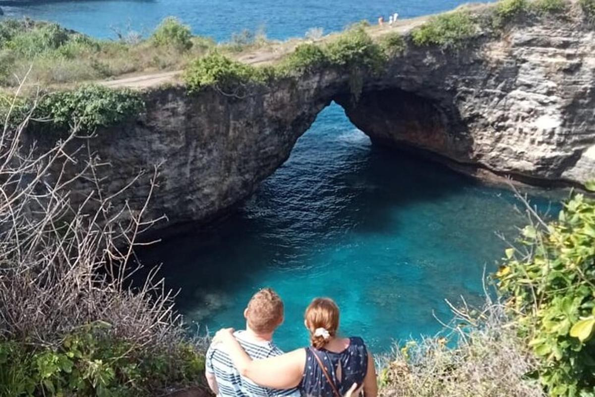 muž a žena sedící na útesu poblíž jeskyně