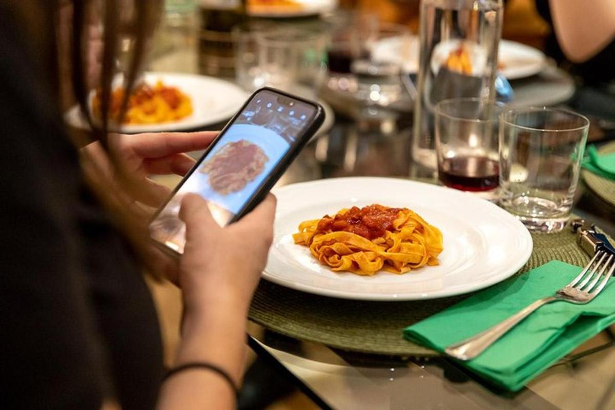 uma pessoa tirando uma foto de um prato de macarrão