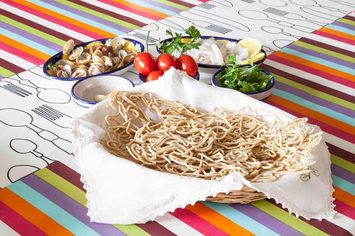 Una canasta de espaguetis sobre una mesa con platos de comida.