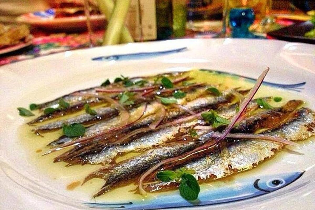 ένα πιάτο ψάρι με σάλτσα και χόρτα πάνω του