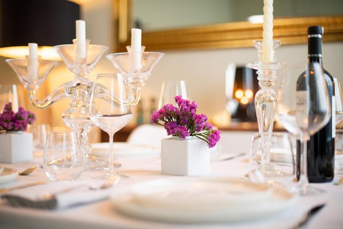 uma mesa com taças de vinho, velas e flores roxas